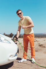 Replenishing vehicle. Dark-haired smiling man replenishing his vehicle on the way home with his...