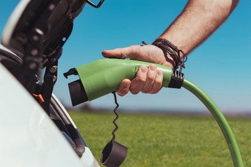 Man with car. Strong handsome man wearing nice black bracelet refueling his white car