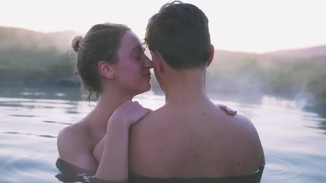 Happy couple in love bathing and relaxing in hot pool in wild landscape