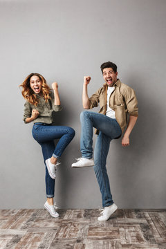 Full length portrait of a joyful young couple jumping