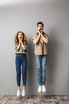 Full length portrait of a shocked young couple jumping