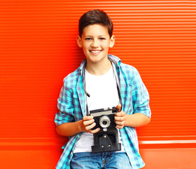 Portrait happy smiling teenager boy with retro camera on a red background