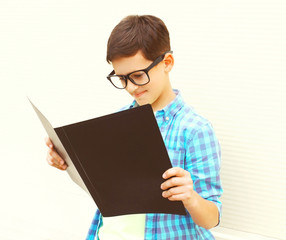 teenager boy in eyeglasses is looking or reading book on white background