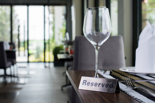 Reserved sign on a table in restaurant. Empty glasses set in restaurant