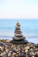 Stones balance and wellness retro spa concept. Close-up pyramid from stones stack over sea. Clear color.