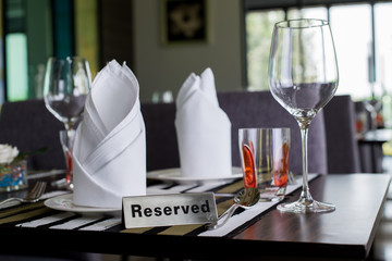 Reserved sign on a table in restaurant. Empty glasses set in restaurant