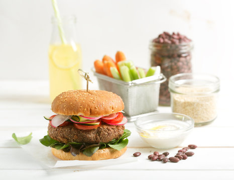 Vegetarian bean and quinoa burger with fresh vegetables and lemonade on the table