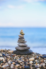 Fototapeta na wymiar Stones balance and wellness retro spa concept. Close-up pyramid from stones stack over sea. Easy toning