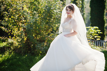 Portrait of a bride dancing alone in the park on a beautiful sunny wedding day.