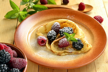 Pancakes, fresh berries sprinkled with powdered sugar - delicious breakfast