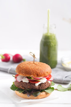 Veggie bean and quinoa burger with fresh vegetables served with green organic smoothie