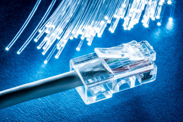Network cable and optical fibers with lights in the ends at the background.
