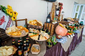 Close-up photo of sour and salty snacks on the wedding banquet along with bottles of beer.