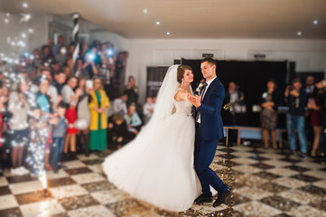 Gorgeous wedding couple performing their first dance with confetti, colorful lights and fireworks.