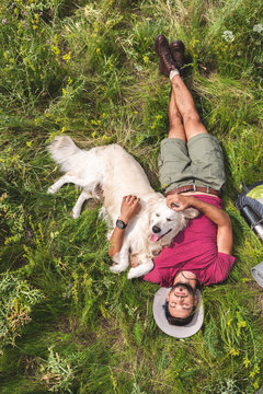 top view of tourist and golden retriever dog lying on green grass