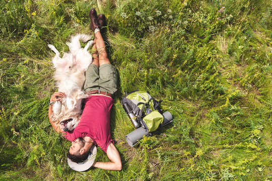 top view of tourist and dog lying on green grass with backpack