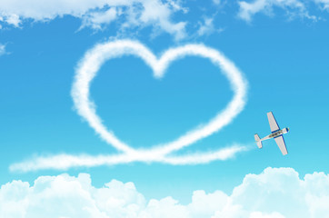 Love figurative heart from a white smoke trail light-engine airplane among the clouds.