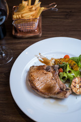 Grilled pork steak. Delicious grilled pork chops with strips sprinkled with fresh coriander served on white plate,