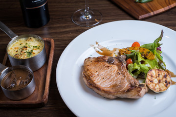 Grilled pork steak. Delicious grilled pork chops with strips sprinkled with fresh coriander served on white plate,