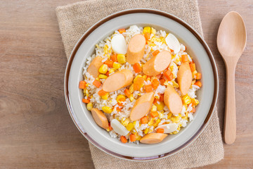top view of fried rice with sausage and vegetable in a ceramic dish on wooden table. homemade style food concept.