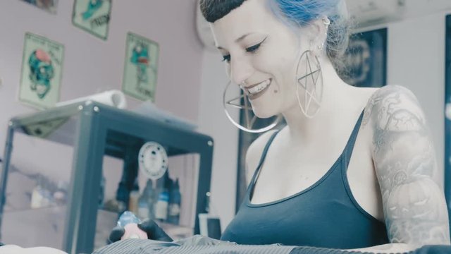Tattoo artist making tattoo of the skull on the woman's belly