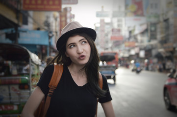 Young asian happy woman traveler with a backpack on her shoulder and travel hat standing over China town, Bangkok, Thailand, Travel holiday relaxation concept