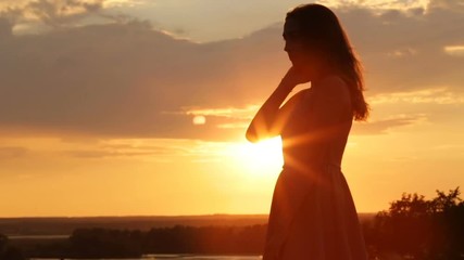 silhouette of young woman in field at sunset, girl walking in nature and enjoying landscape