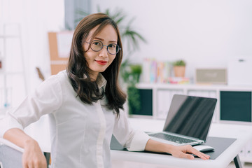 Happy young businesswoman with glasses working on computer laptop in home office