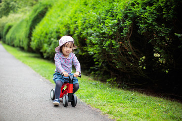 baby girl play bike at Summer forest park
