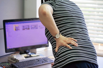 Close-up view of a office worker woman with pain in kidneys. Woman with back ache clasping her hand...