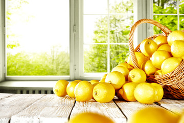 Fresh yellow lemon on white wooden table and free space for your bottle or glass. Window background...