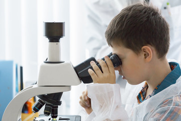 boy  in the lab looking through a microscope