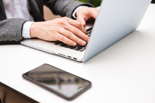 Close up of male hands typing on laptop computer