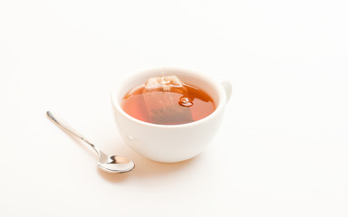 Mug filled with hot water and dipped bag of black tea. Process of black tea brewing in ceramic mug....