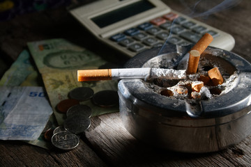 cigarette and calculator with money. in Concept how many cost you pay to buy cigarette in year...
