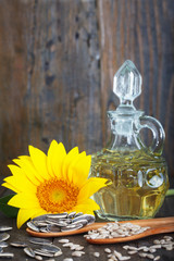 Sunflowers, sunflower oil and sunflower seeds in wooden spoons, vertical image. Organic, healthy food.