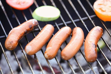 Cooking of sausages and vegetables on barbecue grill, closeup