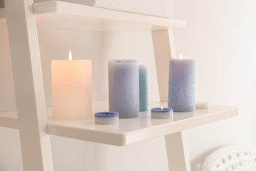 Fototapeta na wymiar Burning wax candles on shelf