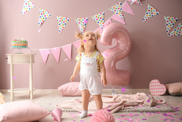 Cute little girl in room decorated for second birthday party