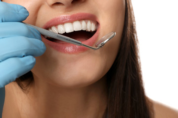 Beautiful young woman with dental mirror on white background