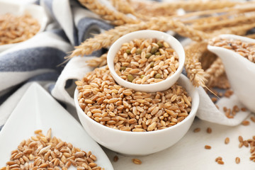 Bowls with wheat grains on white table