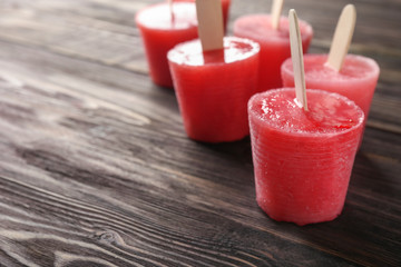 Delicious strawberry popsicles on wooden table