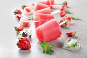 Delicious strawberry popsicles with berries on light background