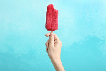 Woman holding delicious strawberry popsicle on color background