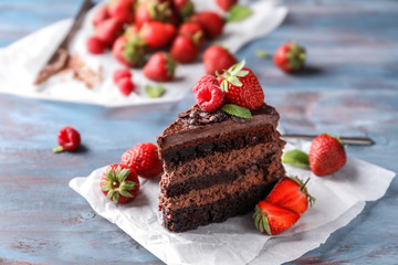 Piece of delicious chocolate cake with berries on wooden table