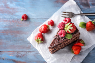 Piece of delicious chocolate cake with berries on wooden table