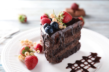 Piece of delicious chocolate cake with berries on plate, closeup