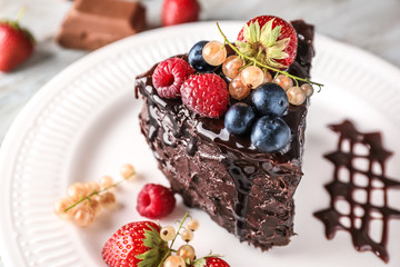 Piece of delicious chocolate cake with berries on plate, closeup