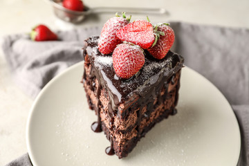 Piece of delicious chocolate cake with strawberry on plate, closeup