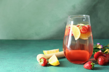 Tasty natural lemonade with strawberries in glass jug on table